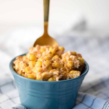 slow cooker creamed corn served in a blue bowl with a spoon