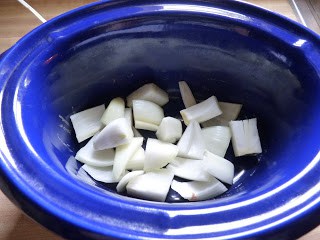 chopped onion on bottom of slow cooker crock