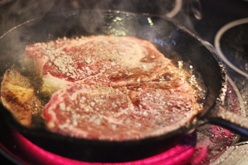 chuck eye steaks cooking in an iron skillet