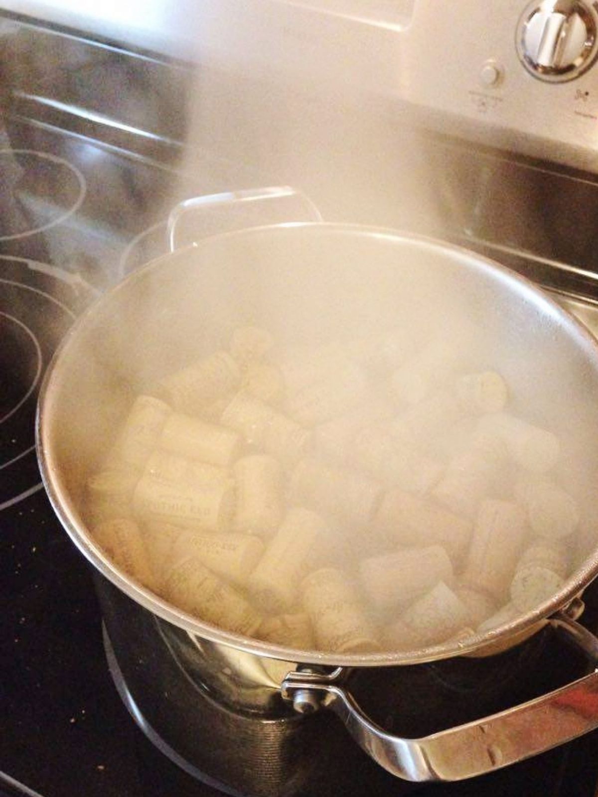 wine corks boiling on the stovetop in a metal pot.