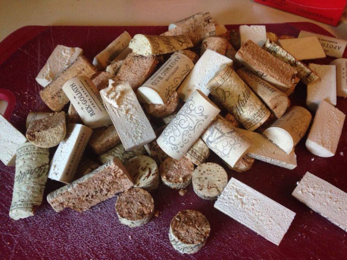Wine corks that have been sliced vertically piled up on a red cutting board.