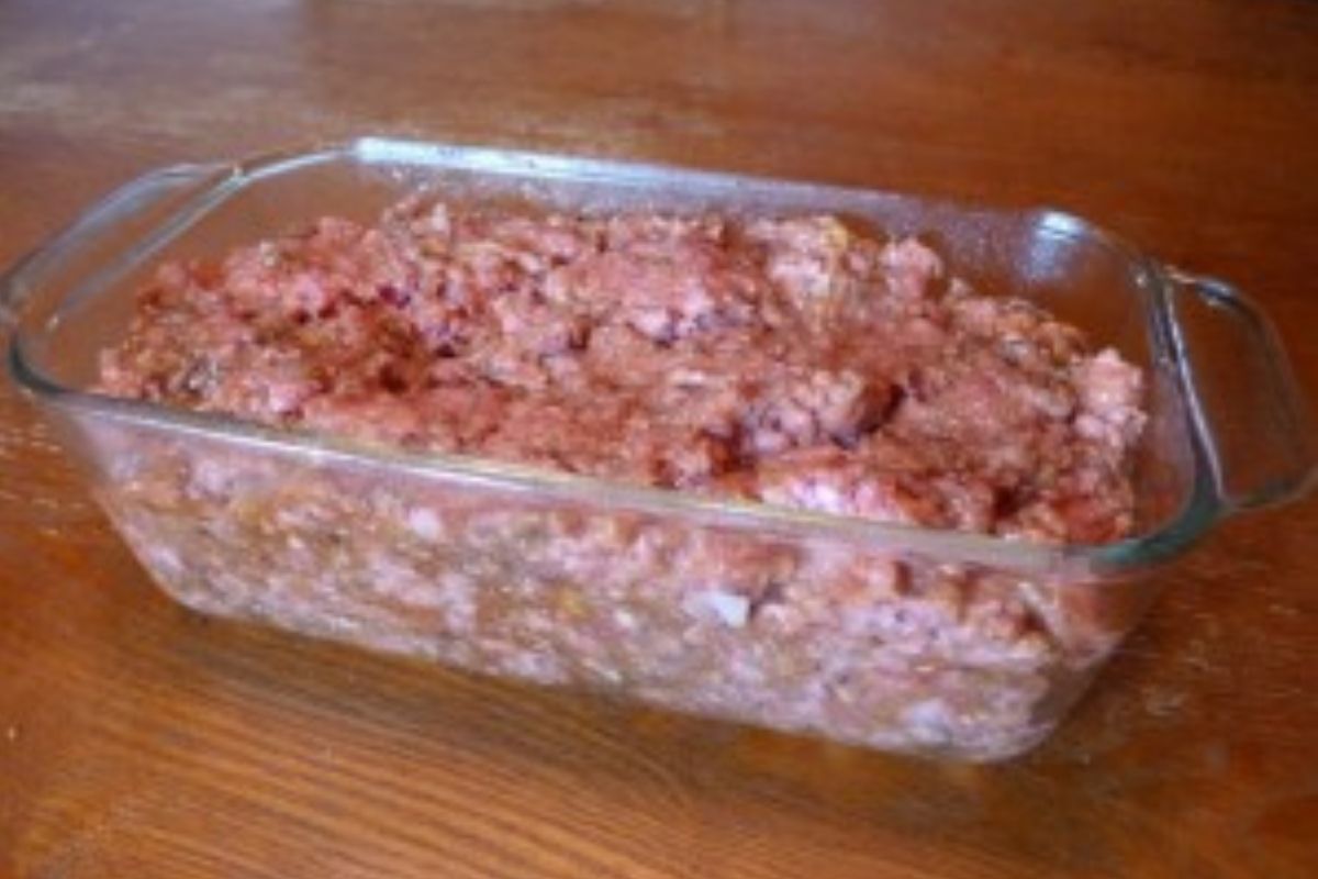 Raw meatloaf pressed into a glass loaf pan ready to go into the oven.