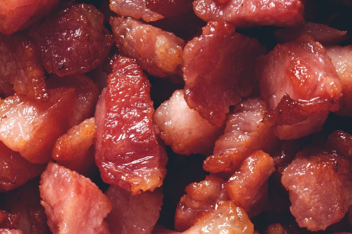 Close up shot of cooked bacon, drained and crumbled by hand.