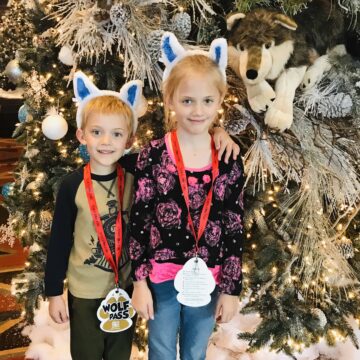 kids wearing christmas wolf ears standing in front of great wolf lodge christmas tree