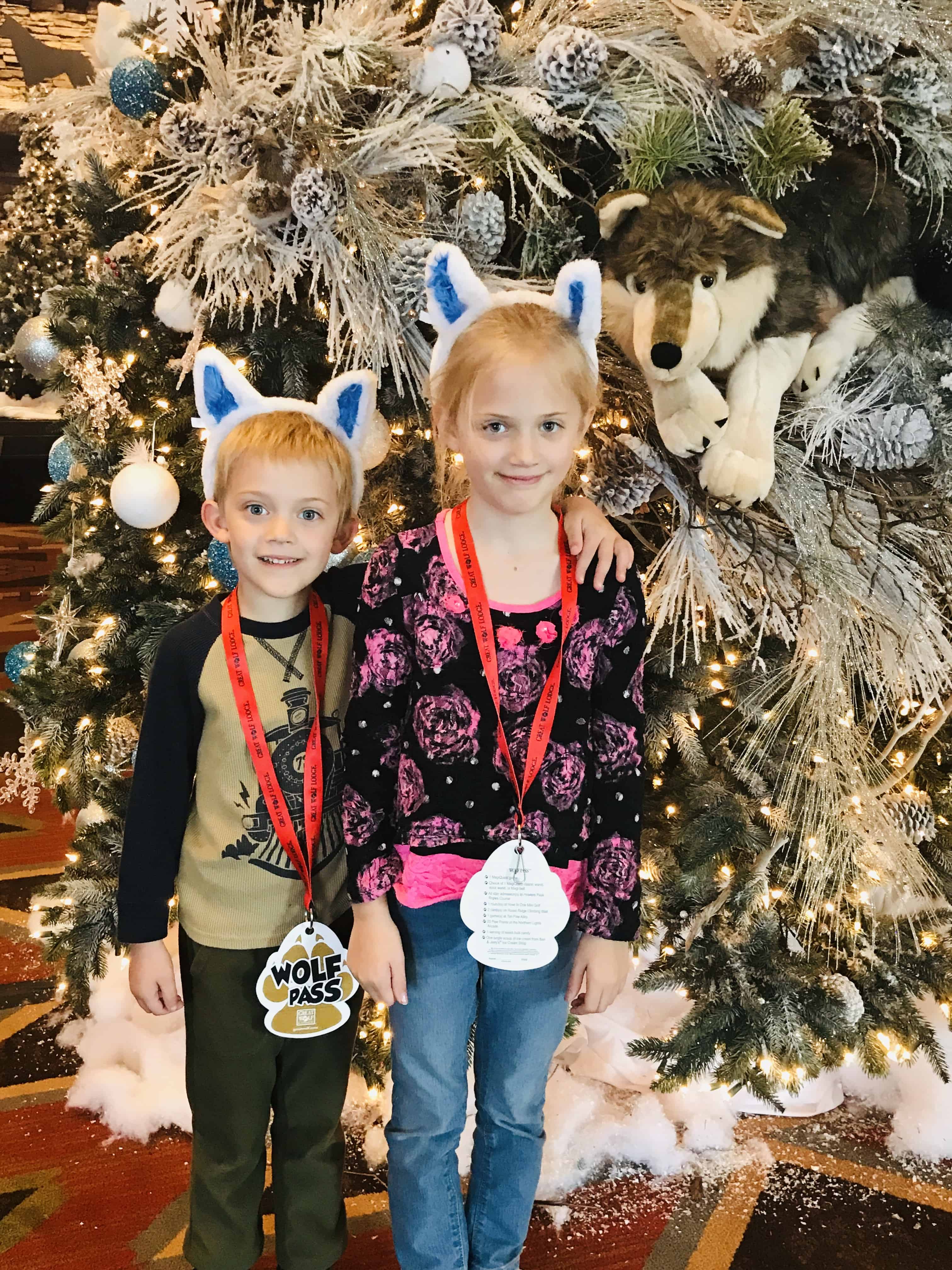 kids wearing christmas wolf ears standing in front of great wolf lodge christmas tree