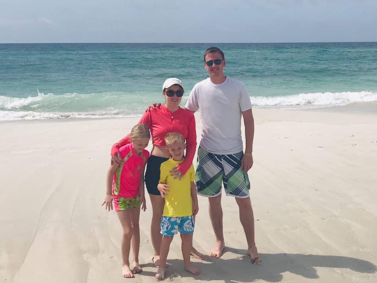 family of four standing on beach in gulf shores alabama.