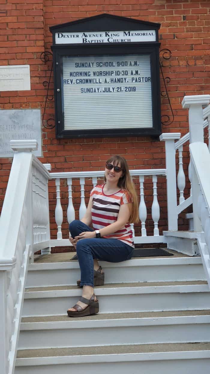 sitting in front of Dexter Avenue King Memorial Baptist Church sign with service times