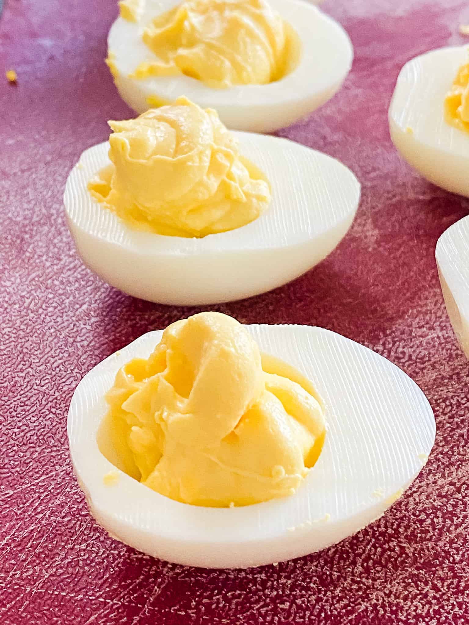 Three instant pot hard boiled eggs sliced in half with the perfect yolks displayed.
