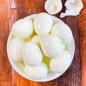 instant pot hard boiled eggs shelled and sitting in a white bowl.