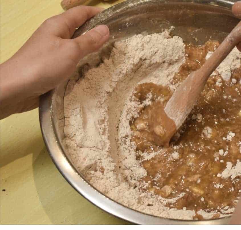 A mixing bowl full of classic gingerbread cookie ingredients being mixed to form dough.