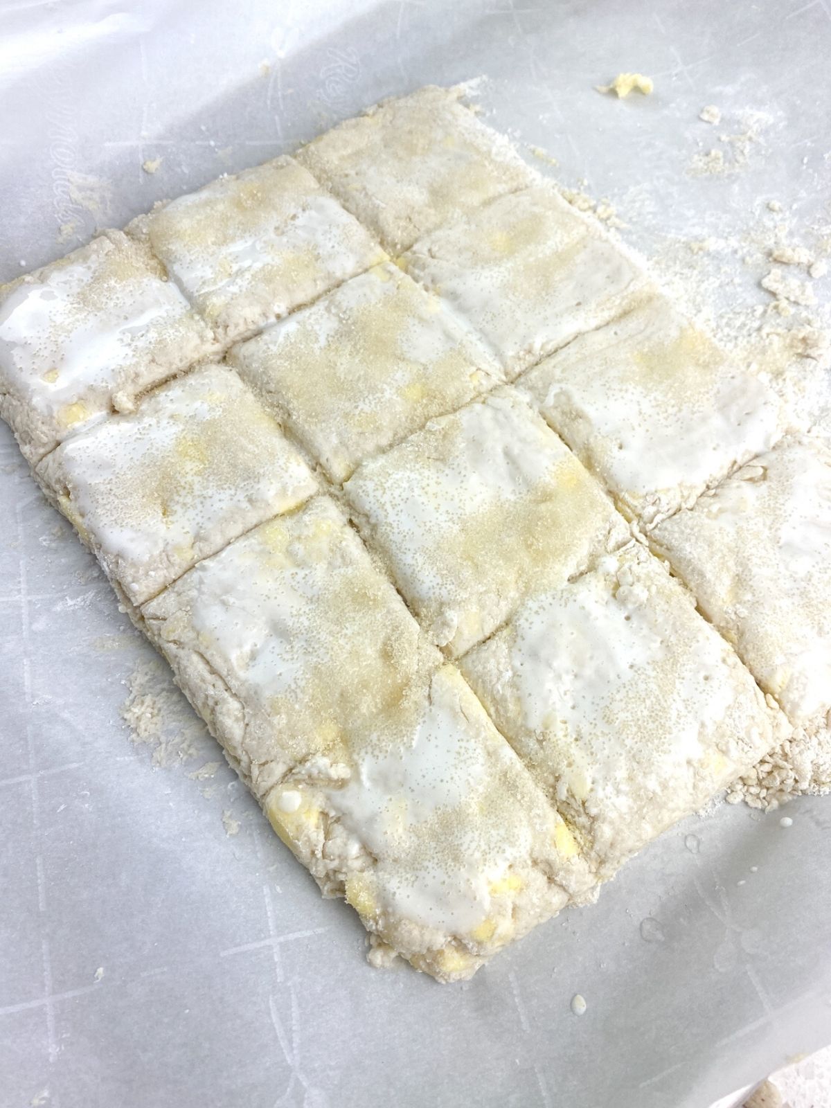 raw biscuit dough cut into 12 squares.