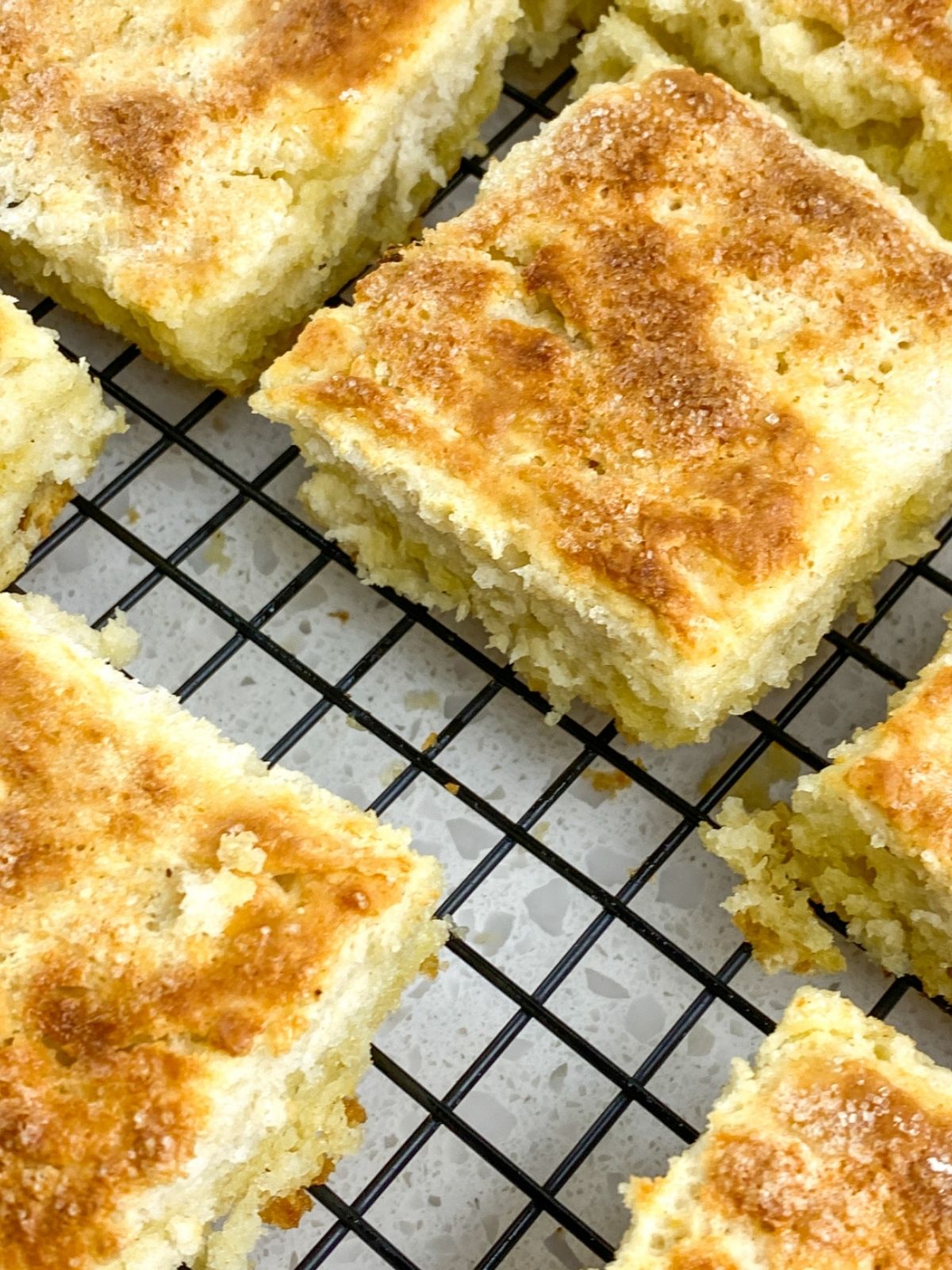 square baked biscuits separated and placed on a black wire cooling rack.