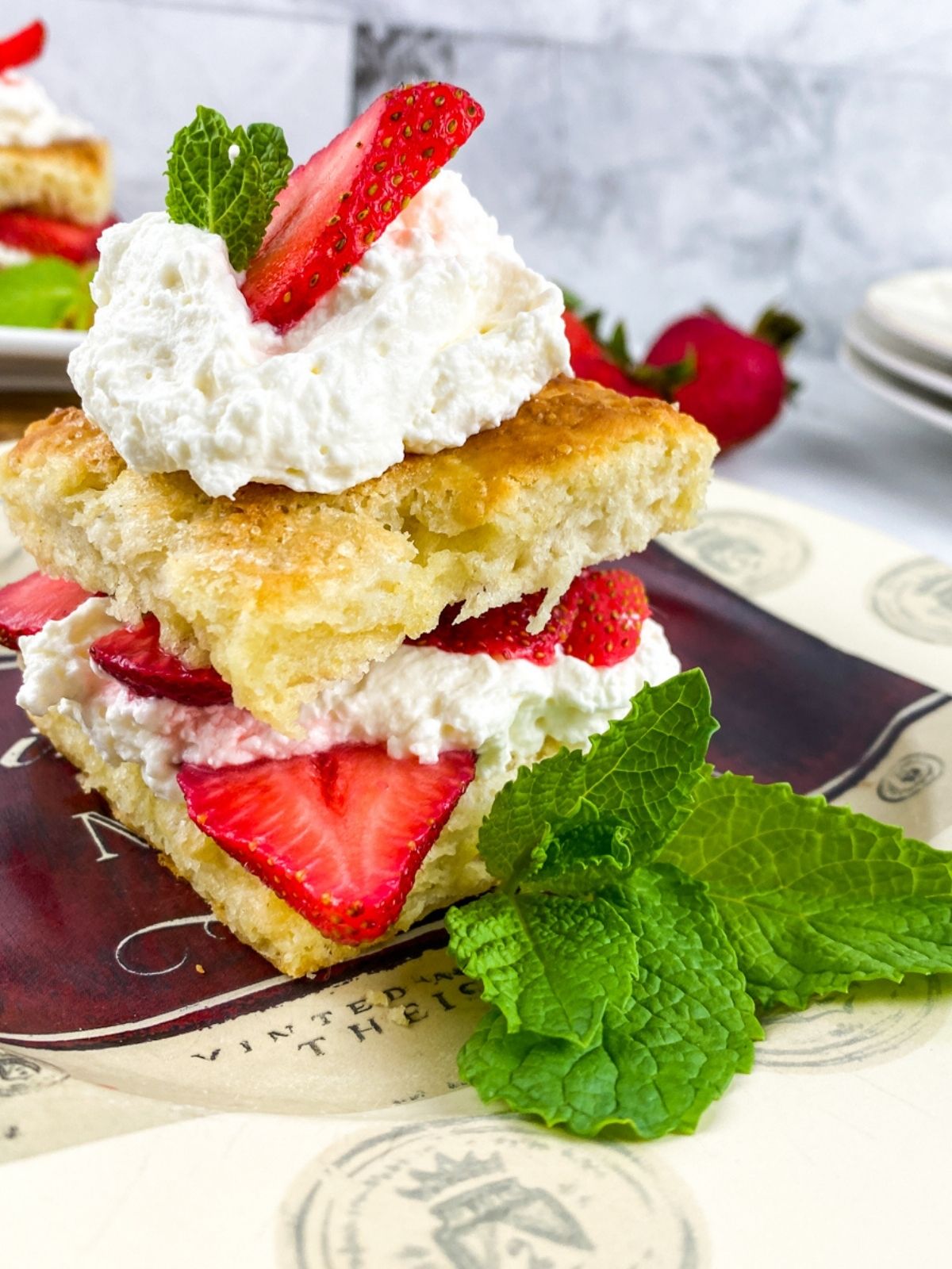 classic strawberry shortcake assembled with strawberries and whipped cream on a plate with a mint garnish.