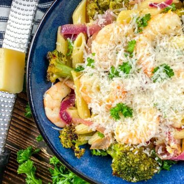 garlic shrimp pasta plated and served with a generous topping of parmesan cheese.