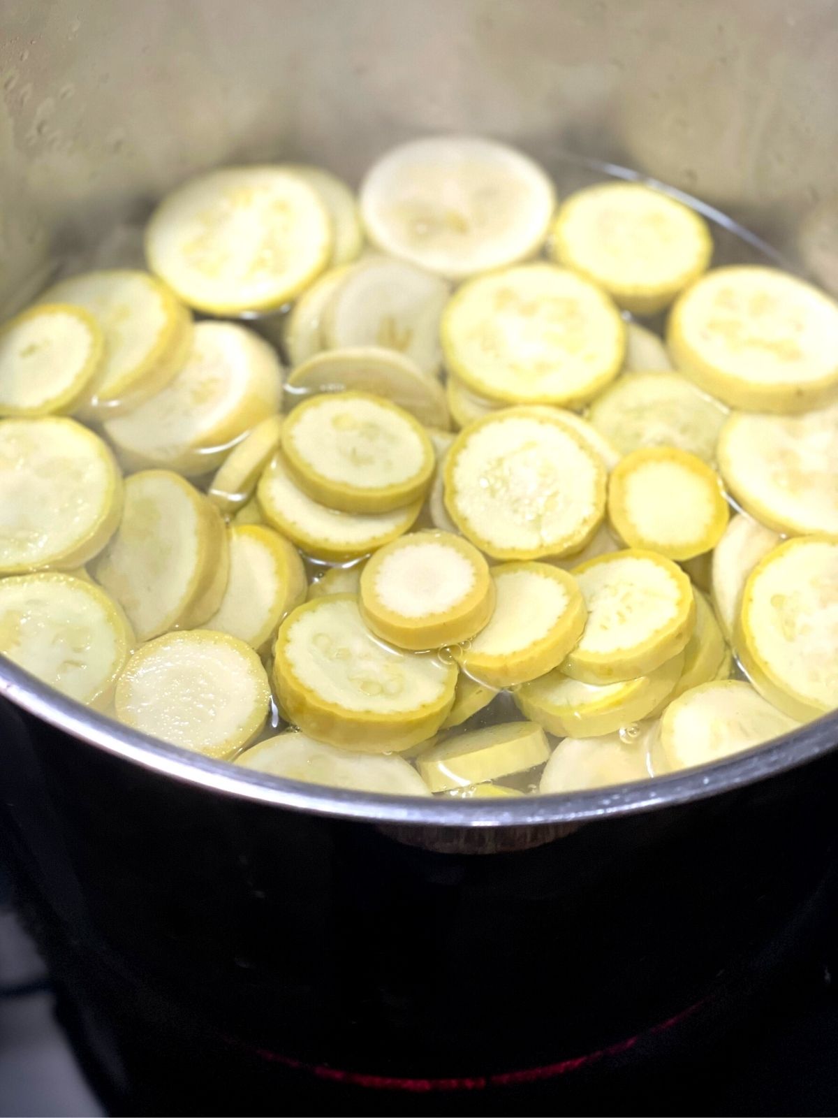 Squash slices being blanched in a large pot of boiling water.