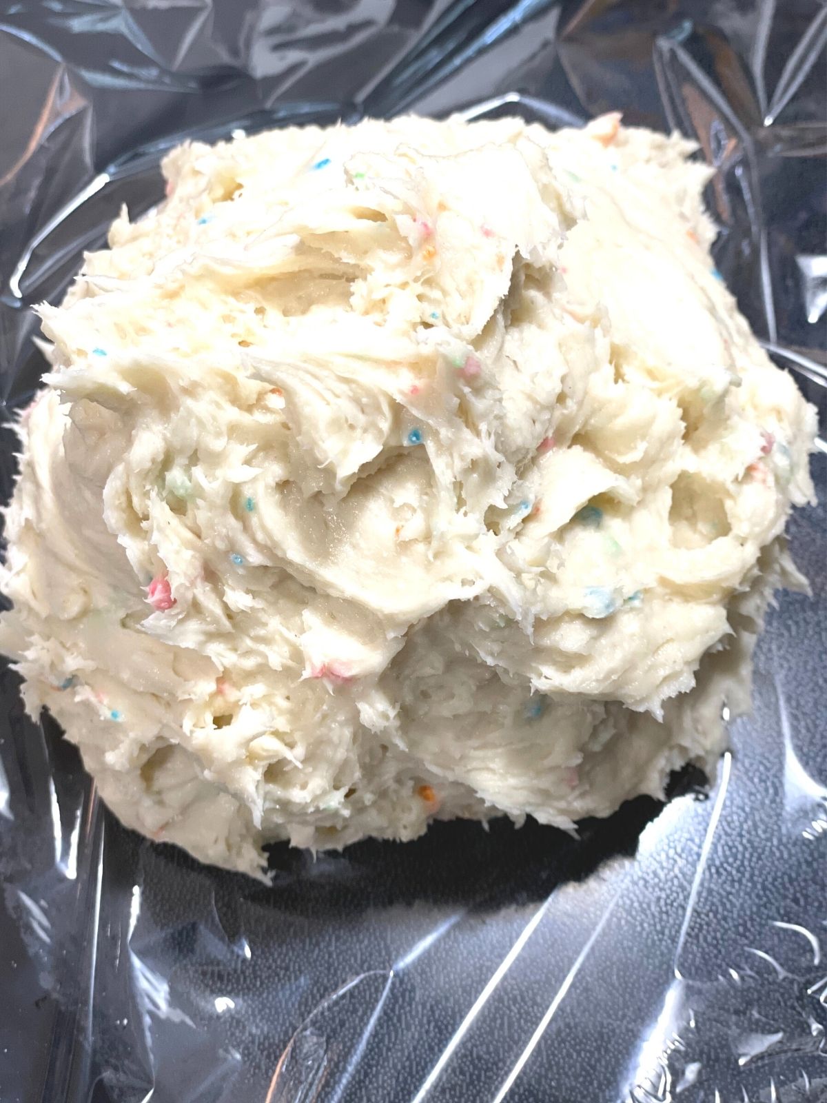 Ball of funfetti dip taken straight from the mixer and placed on plastic wrap.