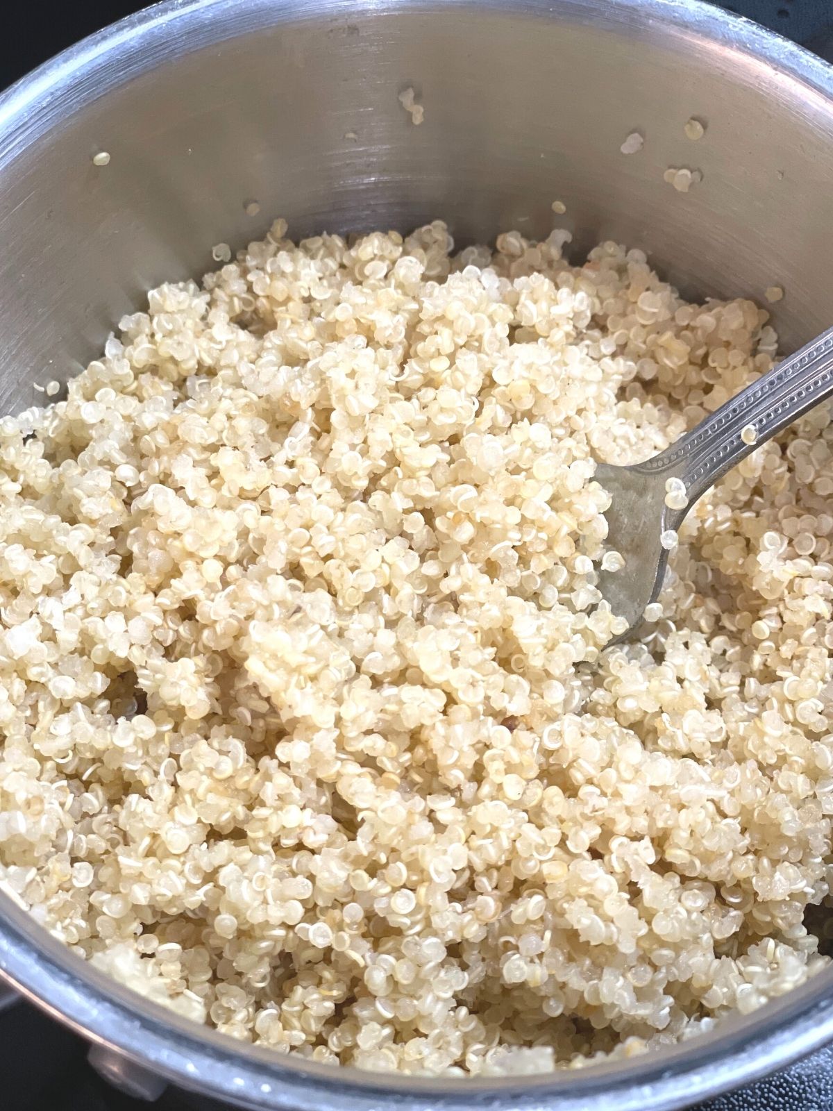 cooked quinoa in a pot with a fork sticking out of the middle.