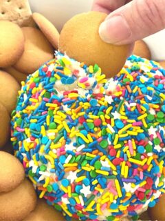 A funfetti cake dip rolled into a ball and covered in sprinkles to make a cake mix dessert served with graham crackers.