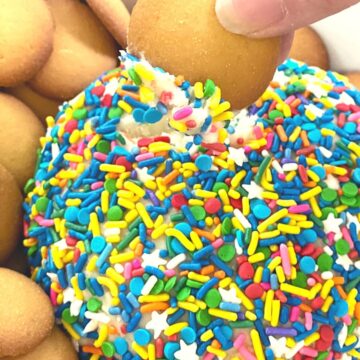 A funfetti cake dip rolled into a ball and covered in sprinkles to make a cake mix dessert served with graham crackers.