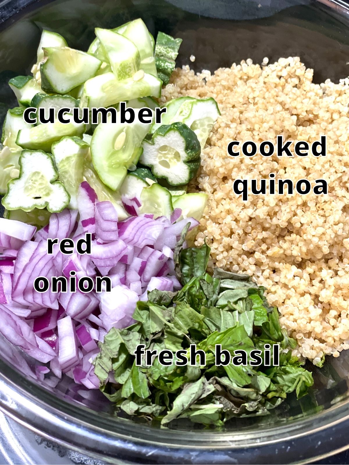 cucumber, quinoa, red onion, and basil in a clear bowl ready to combine.