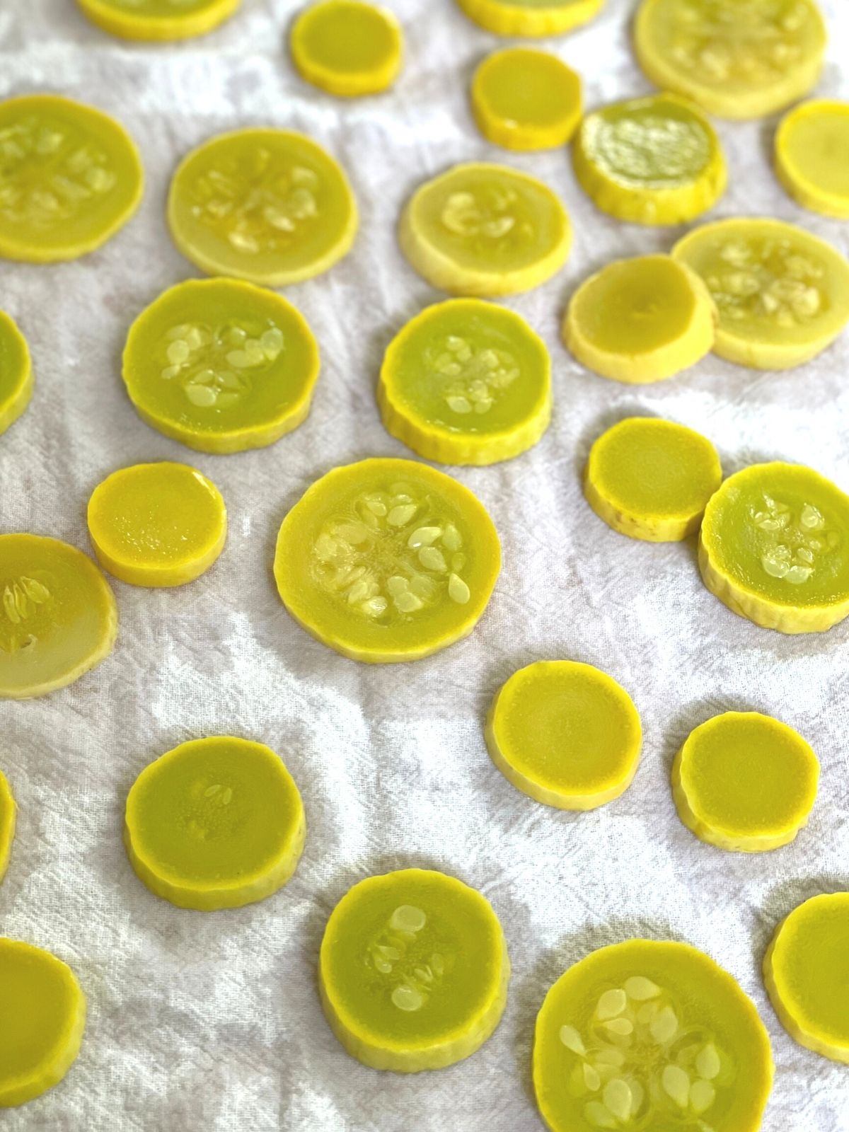 Blanched yellow squash slices drying on a tea towel.