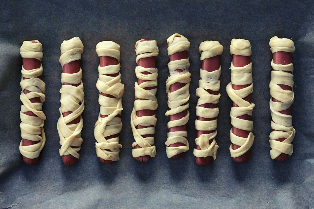 Raw crescent dough wrapped around unheated hot dogs. A space is left about one half inch from the top of each hot dog.