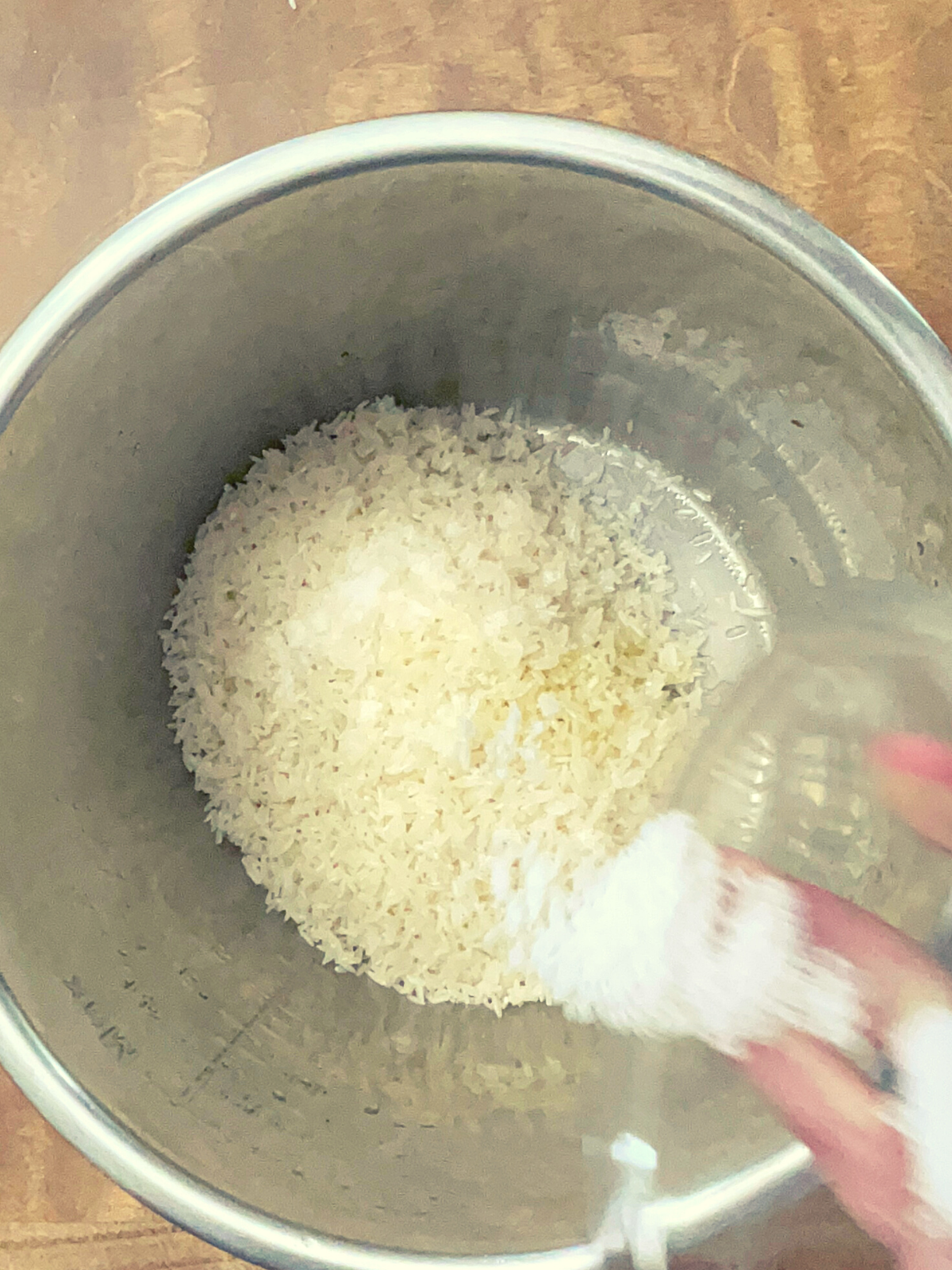 Adding table salt to the Instant Pot of rice and oil.
