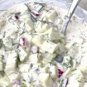 a bowl of creamy cucumber salad mixed together and ready to chill in the refrigerator.