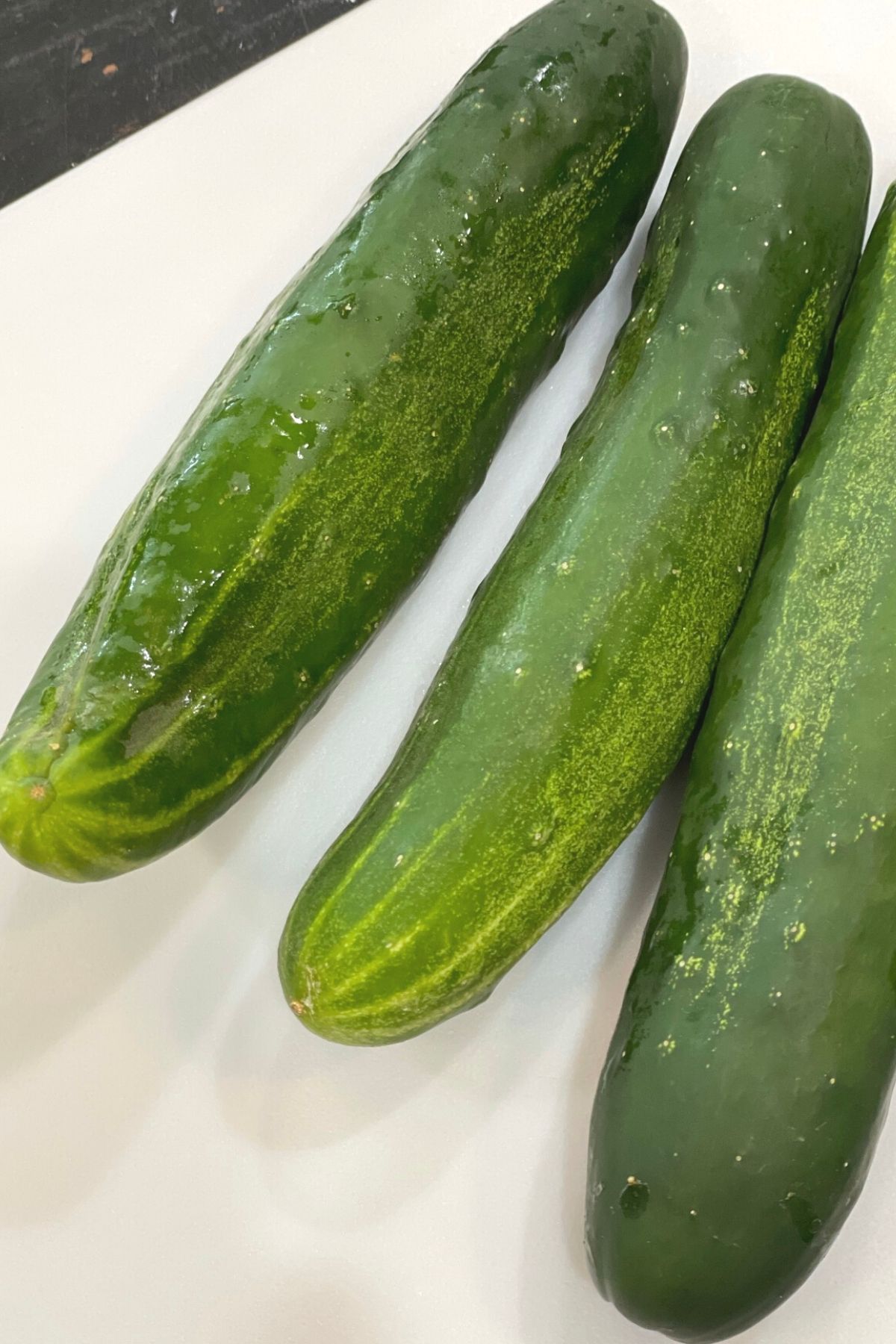 Three large, fresh cucumbers ready to peel and slice.