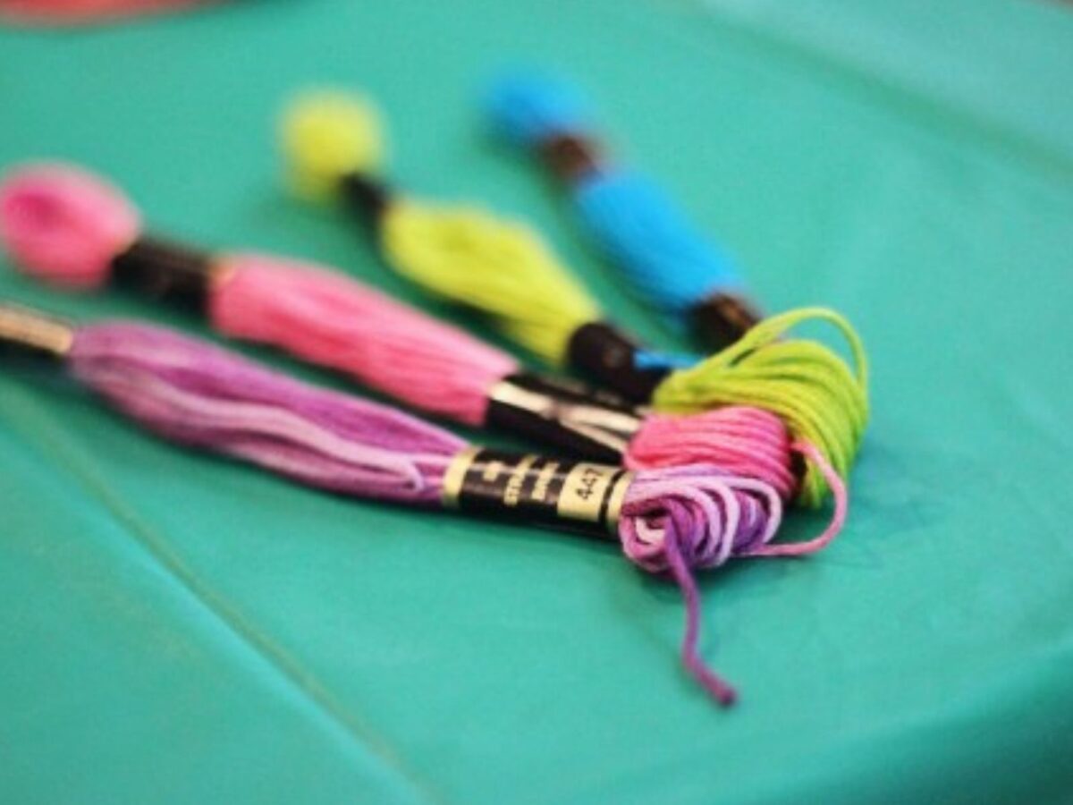 Four skeins of embroidery floss in purple, pink, green, and blue.