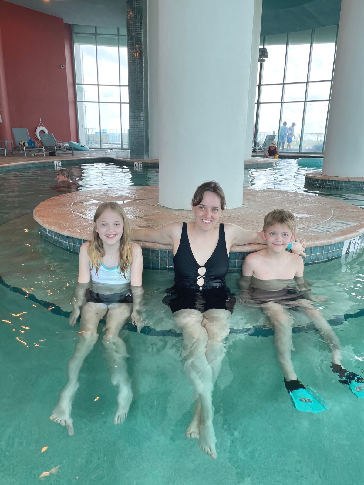 Three people sitting the indoor pool at Turquoise Place.