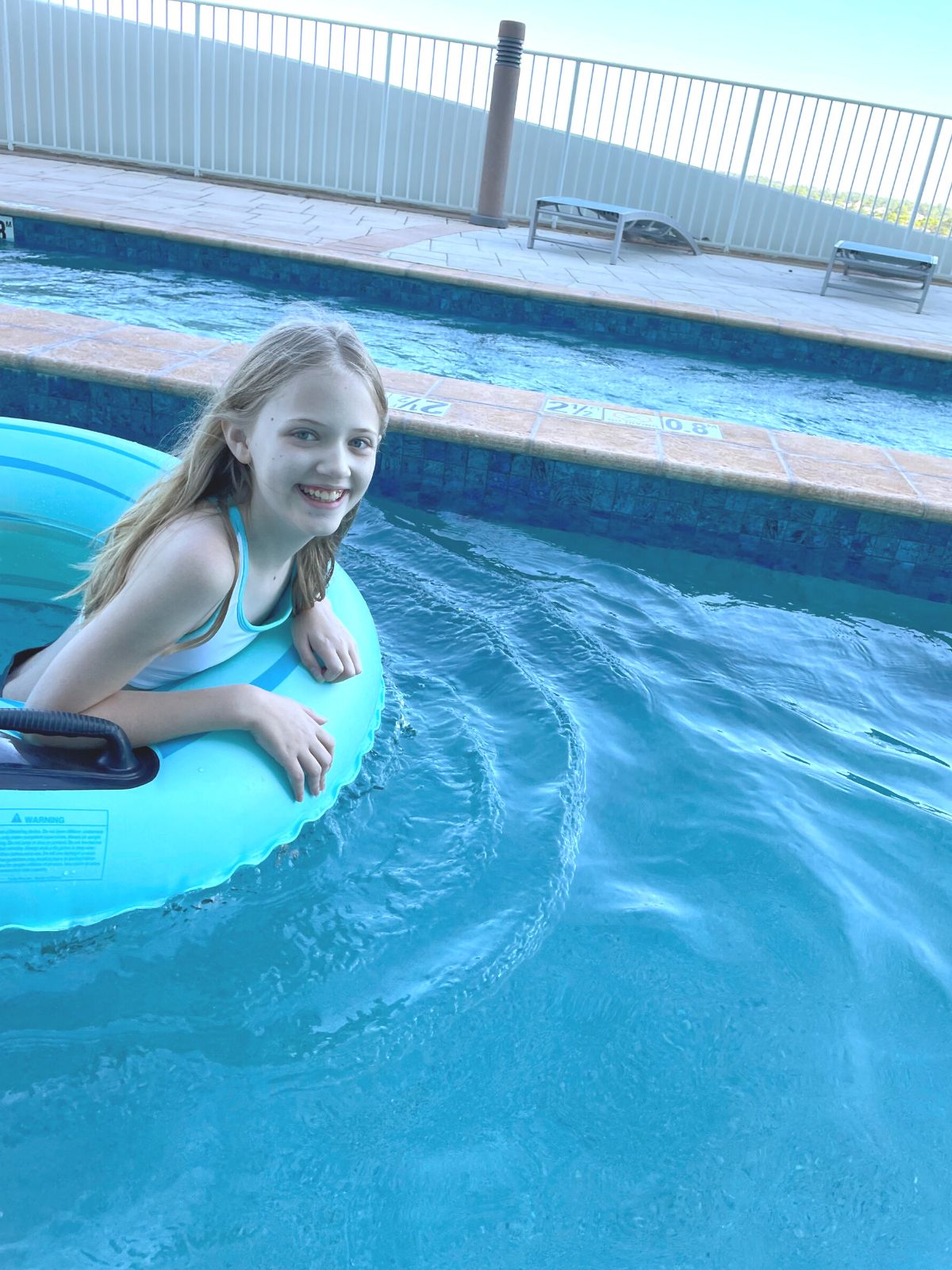 Girl floating in a teal innertube in the lazy river at Turquoise Place.