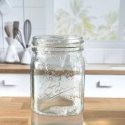 A homemade gnat trap made out of a mason jar resting on a butcher block countertop.