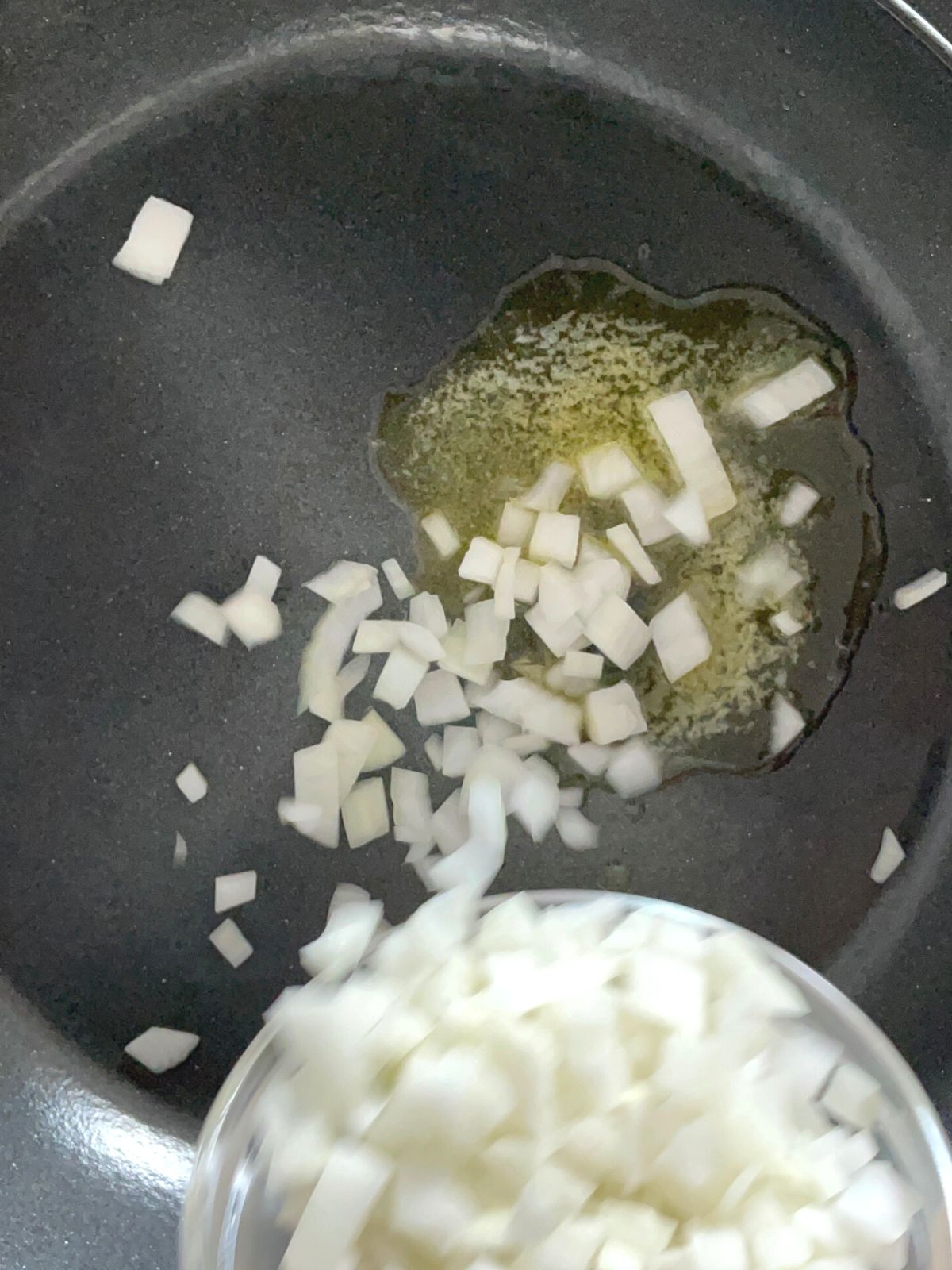 Adding diced onions to hot skillet with melted butter.