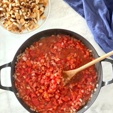 A pot of stewed tomatoes and a plate of toast cut into squares.