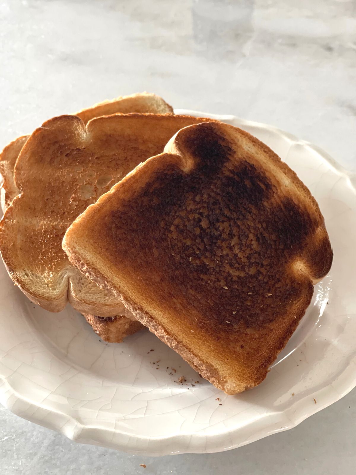 Four pieces of toasted bread arranged on a white plate.