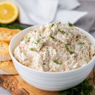 Finished smoked salmon dip topped with dill and served in a bowl.