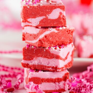 Pink and red strawberry fudge squares stacked on top of one another.