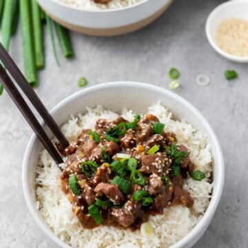A bowl of slow cooker Mongolian beef served over rice.
